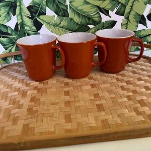 Set of three orange Pyrex mugs